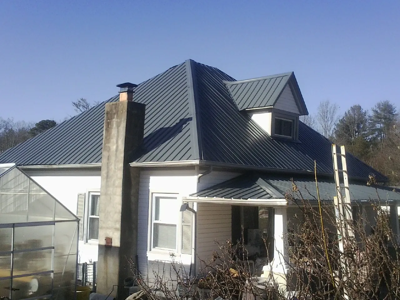Dark blue standing seam metal roof on a white farmhouse with dormer — Slate & Tile Roof Repair by Roofing Brothers in Carpinteria