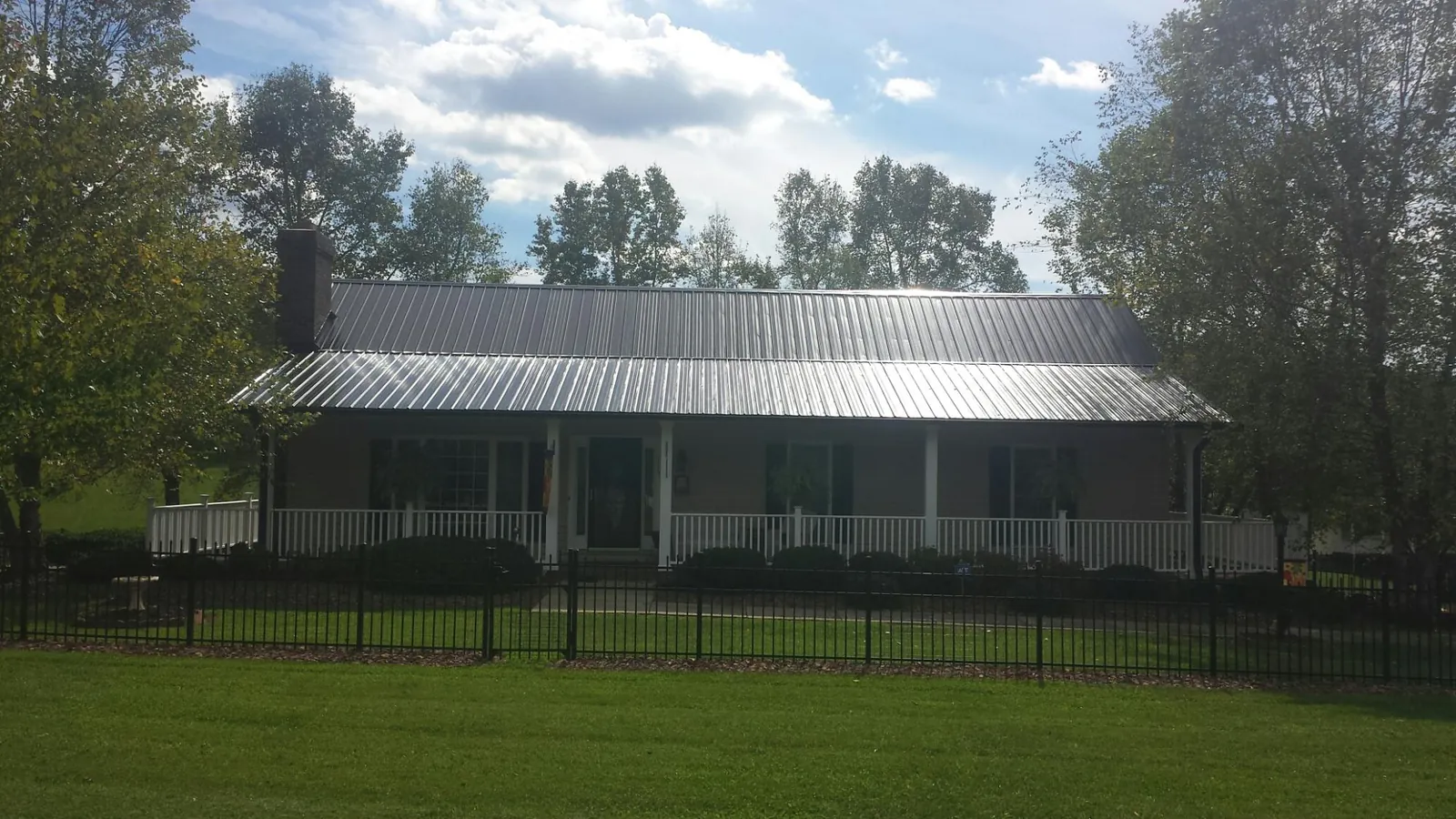 Gray metal roof on a brick ranch with a full width front porch — Gutter Guard Installation work by our crew in Carpinteria