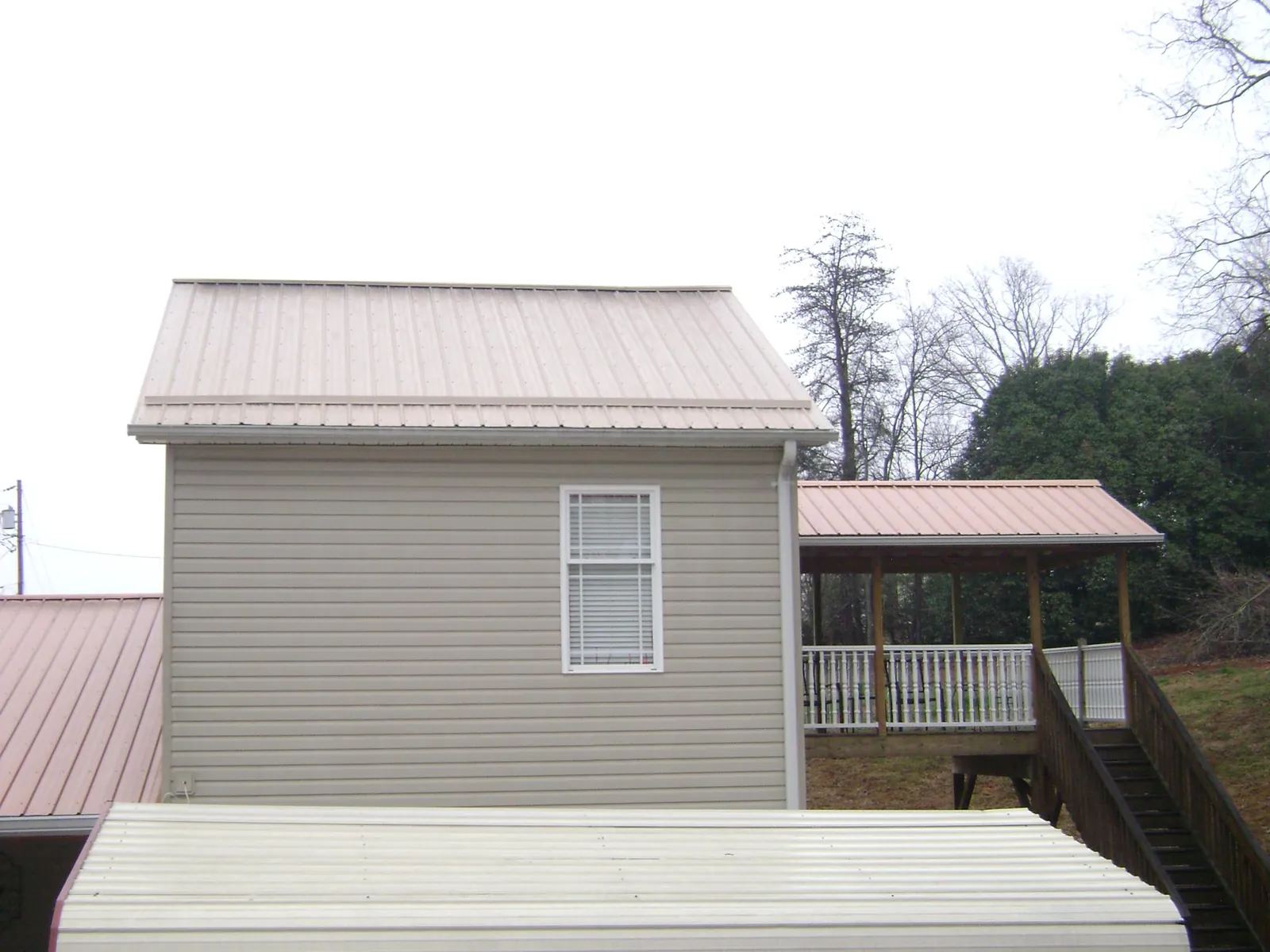 Tan metal roofs on a two story addition and attached porch, from a Roof Replacement job in Carpinteria