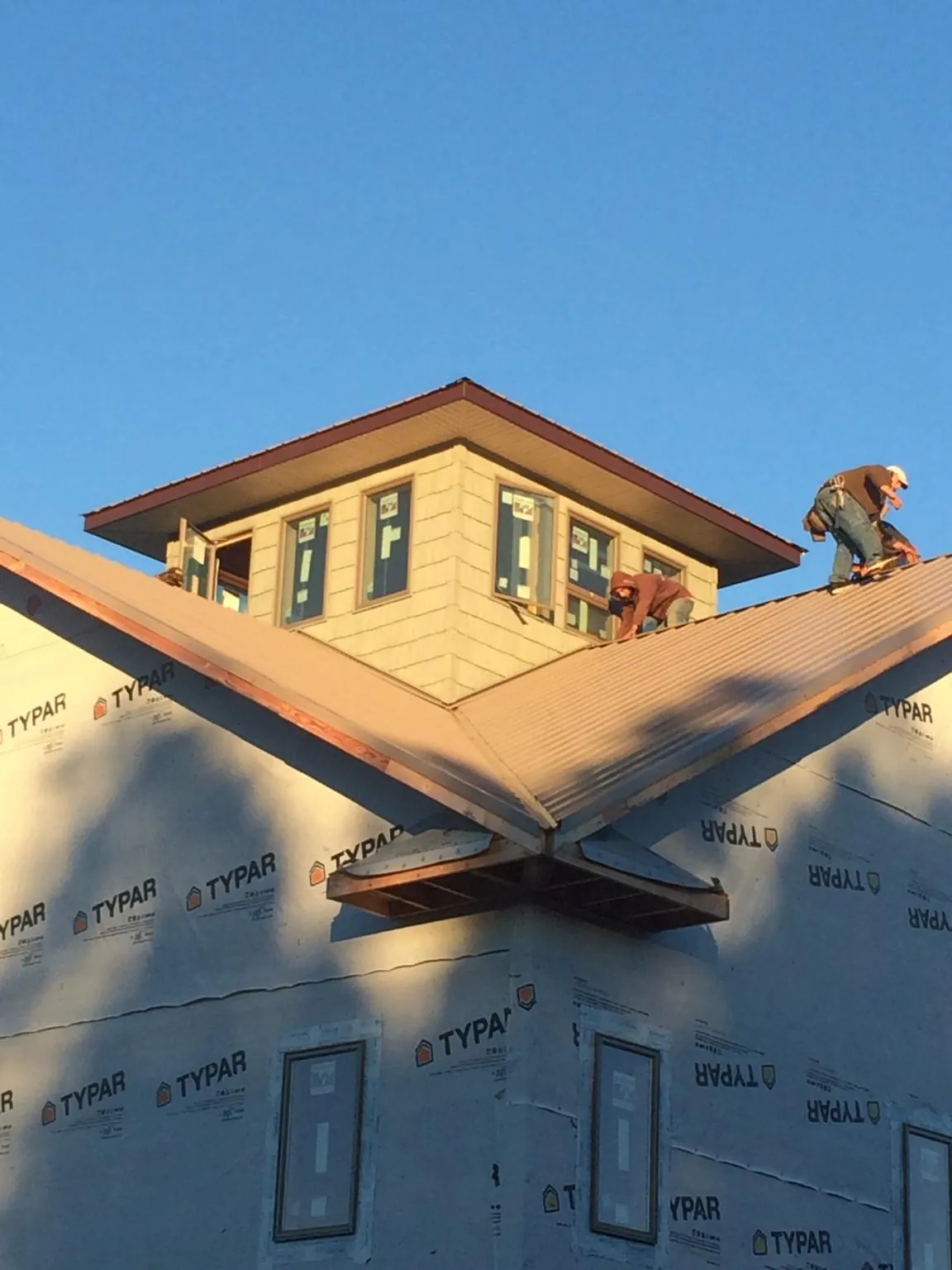 Roofers working around a rooftop cupola on a new metal roof at sunset — Roof Waterproofing in Carpinteria by Roofing Brothers